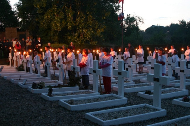Des dizaines d'enfants des écoles portent des flambeaux au milieu des tombes